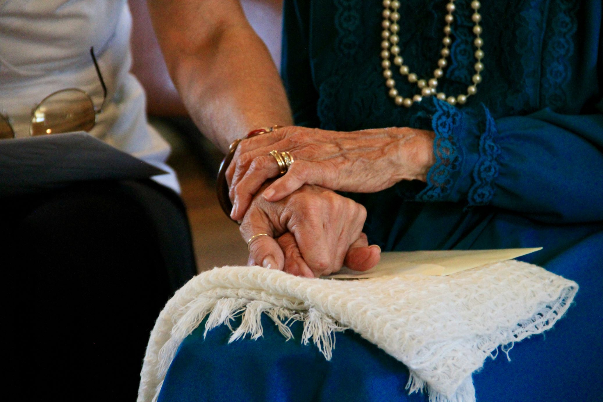 Closeup of senior woman holding the hand of her senior spouse.